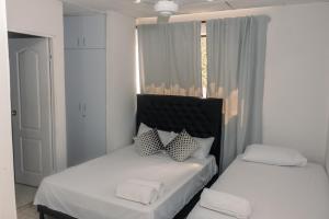 卡塔赫纳Apartamentos Vacacional Cartagena cerca Aeropuerto y Playa的两张带白色床单和枕头的床。