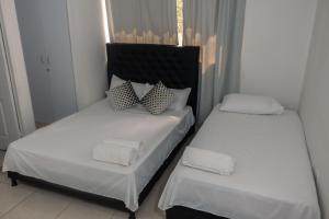 卡塔赫纳Apartamentos Vacacional Cartagena cerca Aeropuerto y Playa的配有2张床的带白色床单和枕头的客房