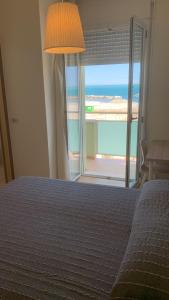 里米尼罗萨蒂酒店的一间卧室设有一张床,享有海景