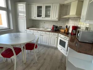 AnsAgréable duplex proche de toutes commodités的厨房配有白色橱柜和桌椅