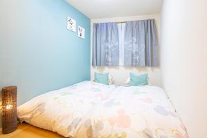 东京CuteFamilyHouse! 3LDK 6minShinjuku 3minJRsta Cozy,Fun,Bright! KidsFree Under6yrs的一间小卧室,配有一张带被子的床