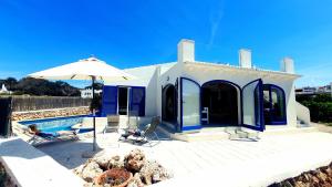 比尼贝卡Binibeca Vell Luxury Villa, sea direct access, private pool的蓝色和白色的房子,设有游泳池和遮阳伞
