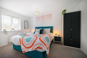 考文垂Spacious 3 bed house w/ garden, parking, WiFi, TV的一间卧室配有一张大床和彩色床罩