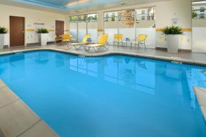 诺克斯维尔Fairfield by Marriott Inn & Suites Knoxville Turkey Creek的酒店大堂的大型游泳池设有黄色的椅子和桌子