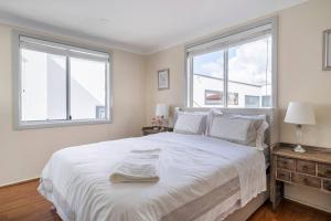 悉尼Amazing Views - 3 Bed Malabar的白色卧室设有一张大床和两个窗户