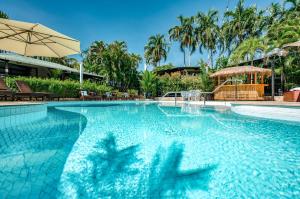 达尔文棕榈城度假酒店的一个带遮阳伞和椅子的游泳池以及树木