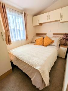 博斯Peacehaven, Ynyslas, Borth的一间小卧室,配有一张带橙色枕头的大床