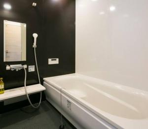 鹿儿岛ROI SPACE 鹿児島的浴室设有白色浴缸及镜子