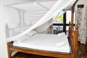 乌昆达Mavericks Convenient Cozy Loft in Diani's CBD的卧室配有带白色床单的天蓬床