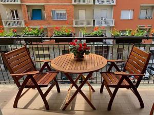 都灵Casa Spezia - Metro Vicina, Wi-Fi Rapido & Netflix的阳台上的木桌和椅子上放着花瓶