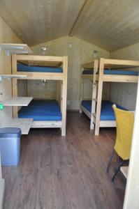 散特Camping Sur En的带三张双层床和黄色椅子的房间