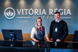 巴乌鲁Vitoria Regia Hotel Bauru的男人和女人站在桌子后面,有电脑