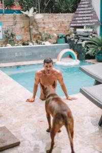 圣胡安Coqui del Mar - LGBTQ Hotel - Adults Only的站在游泳池旁的男人和狗