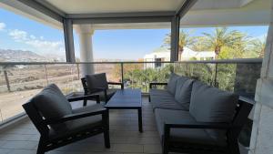 埃拉特דירות נופש רויאל פארק מביאים את הבית לחופשה的阳台设有沙发和桌子,享有美景。