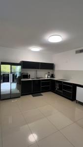 埃拉特דירות נופש רויאל פארק מביאים את הבית לחופשה的厨房配有黑色橱柜和白色瓷砖地板。