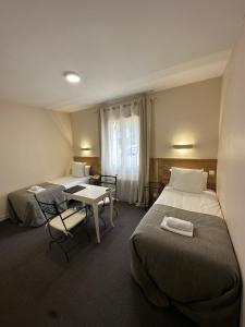 莱塞齐耶德泰阿克Hôtel des Roches - Climatisation的酒店客房设有两张床和一张桌子。