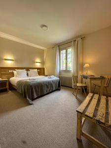 莱塞齐耶德泰阿克Hôtel des Roches - Climatisation的一间卧室配有一张床、一张桌子和一张桌子
