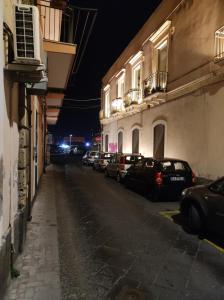 卡塔尼亚Robert holiday apartment的街道,夜间停泊在建筑物旁的汽车