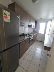 洛斯安第斯Apartamento Los Andes的厨房配有不锈钢冰箱和木制橱柜