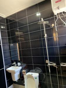 坎帕拉Elvina Home Buziga的黑色瓷砖浴室设有卫生间和水槽