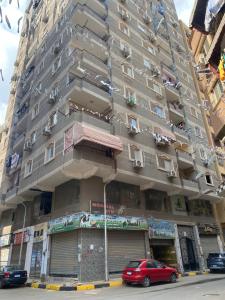 开罗Cozy in Giza 2 bedroom apartment的一座高大的建筑,前面有汽车停放