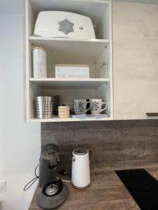拉若瓦尔JARDIN PRIVÉ 2的厨房柜台配有咖啡壶和书架上的杯子