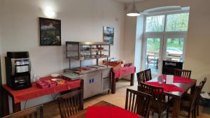 MeznáHotel Stará Škola的一间带红色桌子的餐厅以及一间带炉灶的厨房
