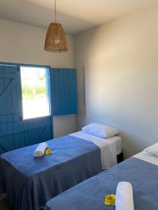 皮廷布Pousada Vila Lua Bela的一间卧室配有两张床、毛巾和窗户