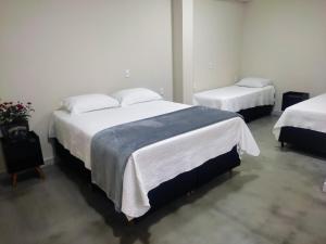 奥兰布拉Pousada Premiatto的一间卧室配有两张带白色床单的床