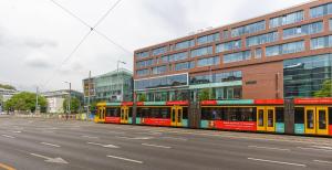 布达佩斯ALLEE BUDA Apartment的一条黄红色的火车在建筑物旁边的街道上