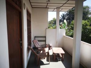 本托塔Sithu Guesthouse的门廊配有两把椅子、一张桌子和一扇窗户