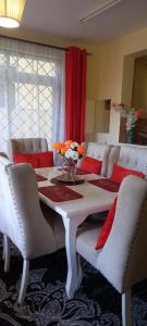 姆特瓦帕Stars Maisonette的餐桌、白色椅子和红色窗帘
