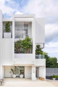 普吉镇The Residence by Andaman Villa的一座白色的建筑,上面有两棵盆栽的树木