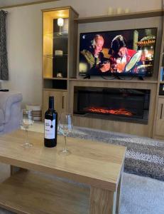 UlromeThe Luxe Lodge, Skipsea Sands Bridlington的客厅的桌子上放有一瓶葡萄酒和两杯酒