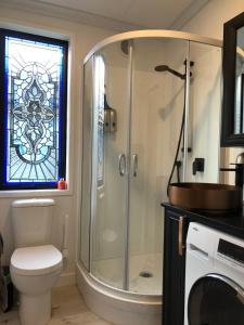 Egmont VillageTiny Home Luxury Farm Escape的带淋浴、卫生间和彩色玻璃窗的浴室