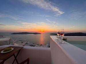 易莫洛林Esmi Suites Santorini的阳台上的两杯葡萄酒,享有日落美景
