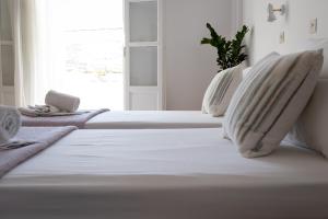 克里希阿克提Seample studios的一张带两个枕头的白色床和窗户