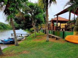 古里里CASA AMARELA Beira Rio Guriri的棕榈树水边的船屋