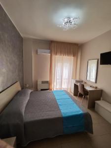 切萨雷奥港阿尔伯格普利玛维拉旅馆的一间卧室配有一张大床、一张书桌和一个窗户。