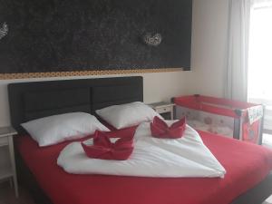 布雷兹诺Apartmán NAVRCHU的一张红色和白色的床,上面有两个红色的弓
