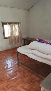 奇旺Chital lodge的一间卧室设有一张床和一个窗户,铺有木地板
