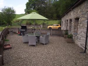 巴拉Cae Coryn Cottages, Snowdonia ( Troed y Graig )的庭院配有桌椅和遮阳伞。