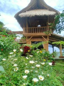BaturitiLembah Cinta Mayungan的树屋,带茅草屋顶和鲜花