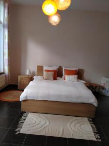 迪南'Nulle Part Ailleurs'的一间卧室配有带白色床单和橙色枕头的床。