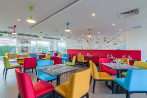 奥托佩尼Ibis Styles Bucharest Airport的用餐室配有色彩缤纷的桌椅