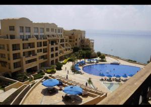 索瓦马Dead Sea view Elite apartment Samara Resort traveler award 2024的享有带蓝色遮阳伞和建筑的游泳池的景致