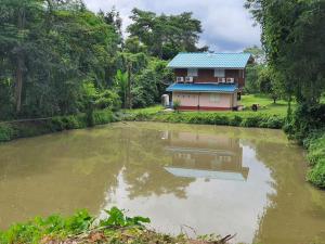 Ban Khok Sawang (2)นาหินลาดรีสอร์ท Nahinlad Resort的房屋前的房屋和池塘