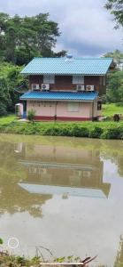 Ban Khok Sawang (2)นาหินลาดรีสอร์ท Nahinlad Resort的水体旁有蓝色屋顶的房子