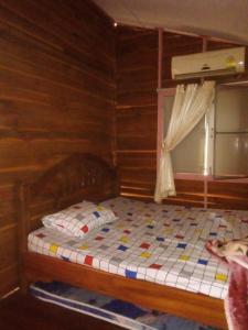 Ban Khok Sawang (2)นาหินลาดรีสอร์ท Nahinlad Resort的木制客房的一张床位,设有窗户