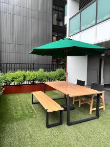 奥克兰3 bedroom apartment in Newmarket的一张带绿伞和两个长椅的野餐桌